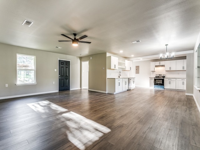 unfurnished living room with a textured ceiling, ceiling fan with notable chandelier, dark hardwood / wood-style floors, and sink