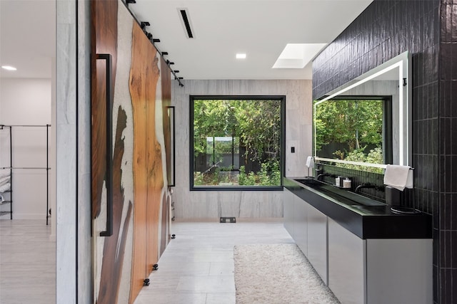 bathroom with tile walls, a wealth of natural light, and a skylight