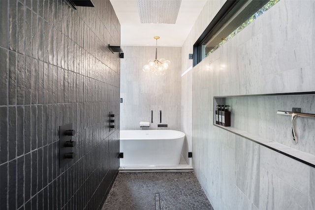 bathroom featuring a chandelier, a bath, and tile walls