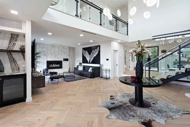 entrance foyer featuring a towering ceiling, a large fireplace, and light parquet flooring