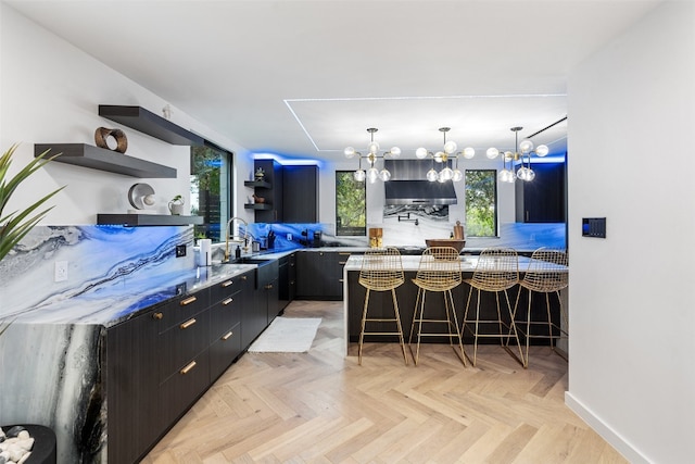 kitchen with light stone countertops, a kitchen breakfast bar, light parquet flooring, and decorative light fixtures