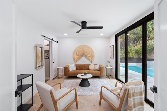 living room with ceiling fan, a barn door, and light parquet flooring