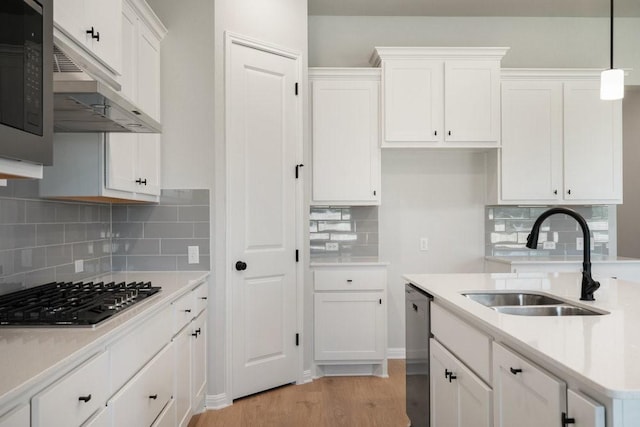 kitchen featuring hanging light fixtures, stainless steel appliances, light wood-type flooring, white cabinets, and sink