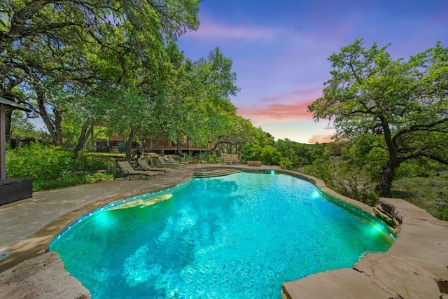 pool at dusk with a patio area