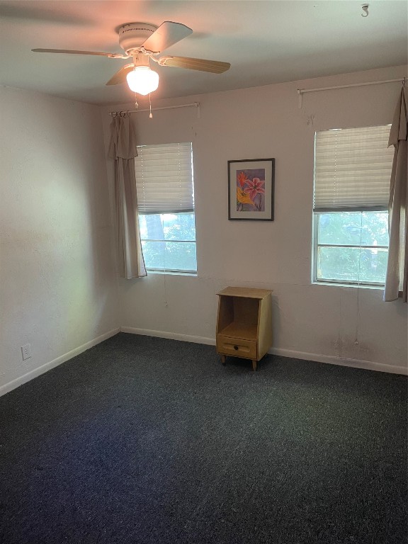 carpeted spare room with ceiling fan