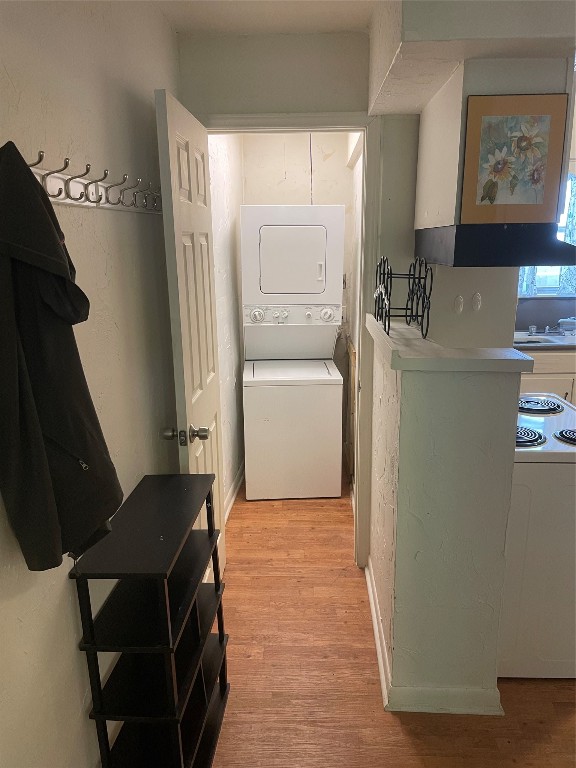 washroom featuring sink, stacked washer and clothes dryer, and light hardwood / wood-style floors