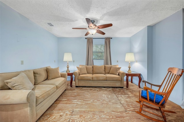 living room with ceiling fan and a textured ceiling