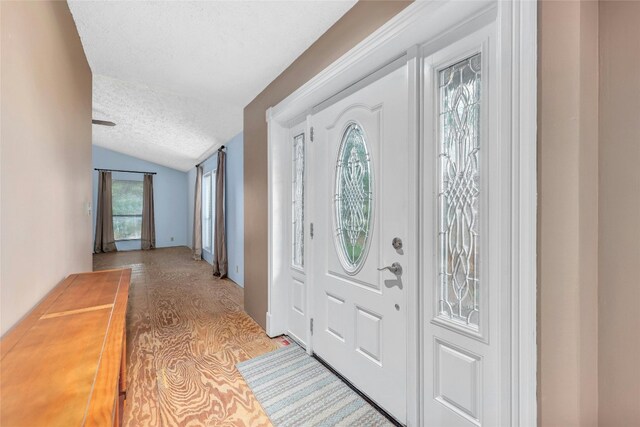 entryway featuring light hardwood / wood-style floors, vaulted ceiling, and a textured ceiling