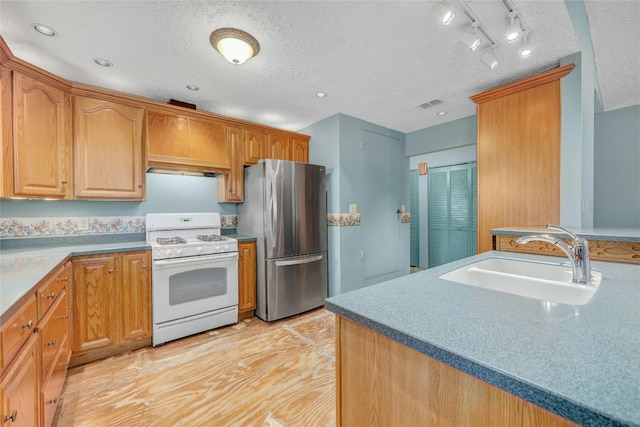 kitchen with stainless steel refrigerator, sink, track lighting, a textured ceiling, and white gas range