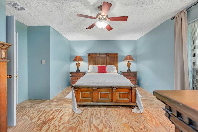 bedroom featuring ceiling fan, light wood-type flooring, and a textured ceiling