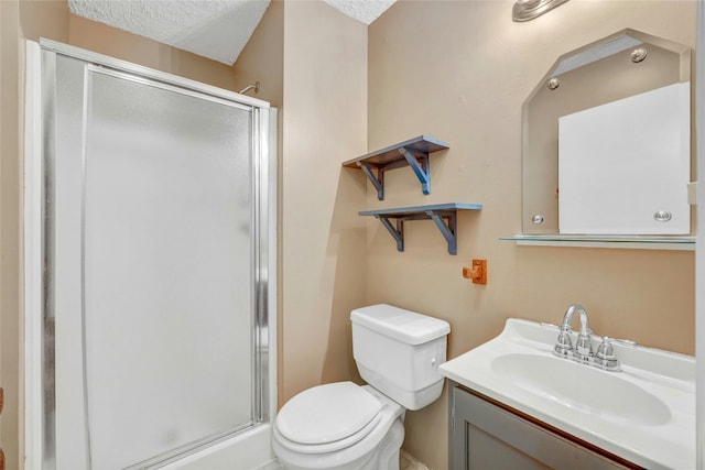 bathroom featuring a textured ceiling, toilet, vanity, and a shower with door