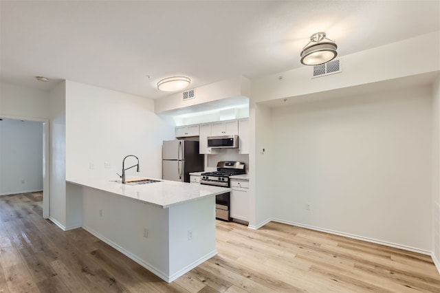 kitchen featuring white cabinetry, sink, light wood-type flooring, and appliances with stainless steel finishes