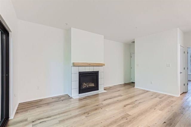 unfurnished living room with a tile fireplace and light wood-type flooring