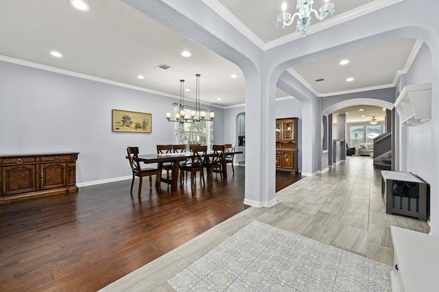 dining area featuring an inviting chandelier, hardwood / wood-style floors, and crown molding