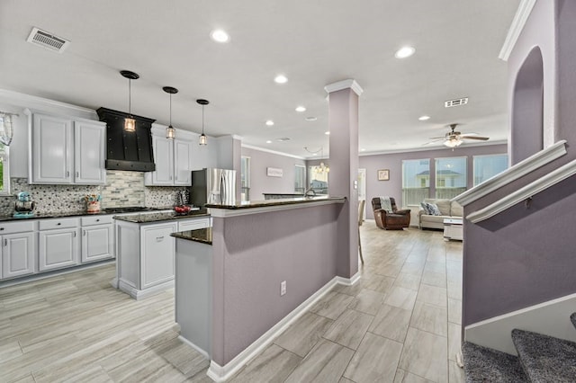 kitchen featuring ceiling fan, hanging light fixtures, stainless steel appliances, backsplash, and kitchen peninsula