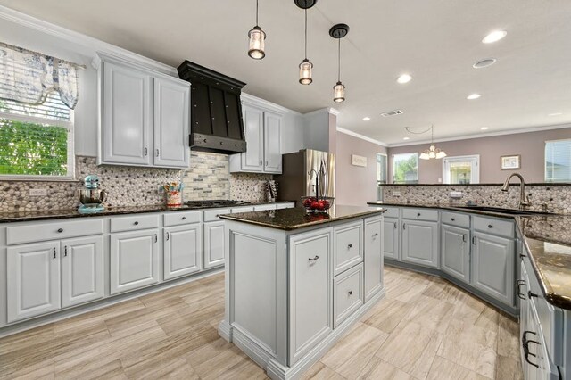 kitchen with dark stone counters, stainless steel appliances, sink, pendant lighting, and a kitchen island