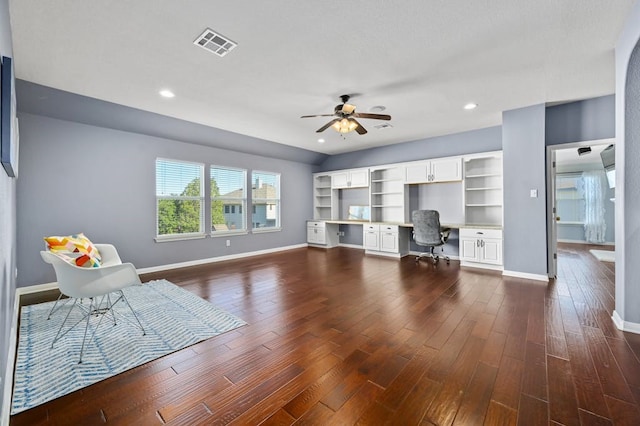 unfurnished office featuring ceiling fan, built in desk, and dark wood-type flooring