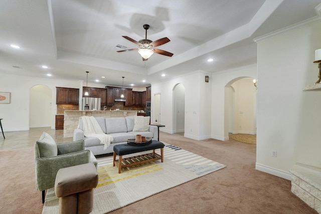 carpeted living room with ceiling fan, ornamental molding, and a tray ceiling