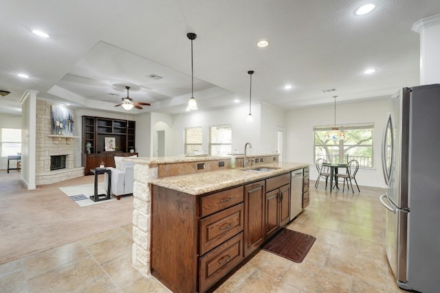 kitchen featuring appliances with stainless steel finishes, sink, pendant lighting, a fireplace, and a large island