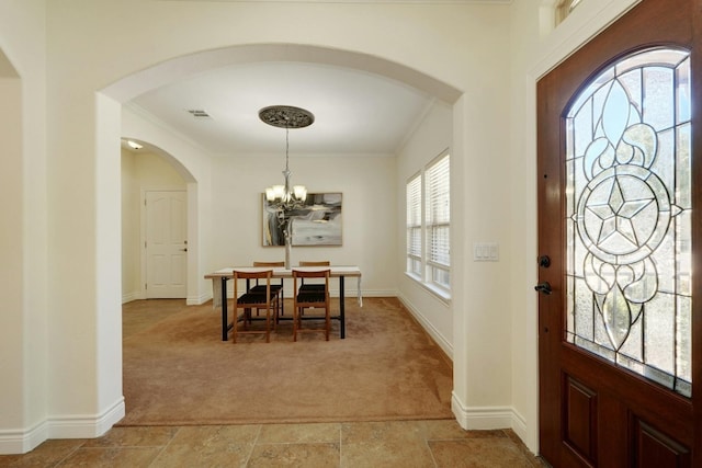 carpeted foyer entrance with crown molding and a notable chandelier