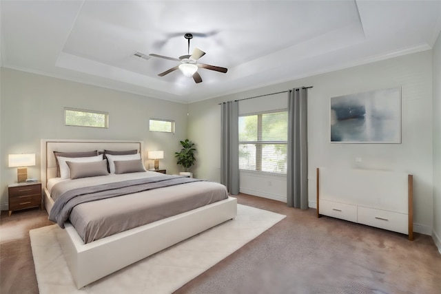 bedroom with ceiling fan, light colored carpet, ornamental molding, and a tray ceiling