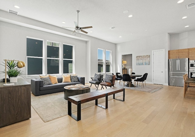 living room with a wealth of natural light, ceiling fan, and light wood-type flooring