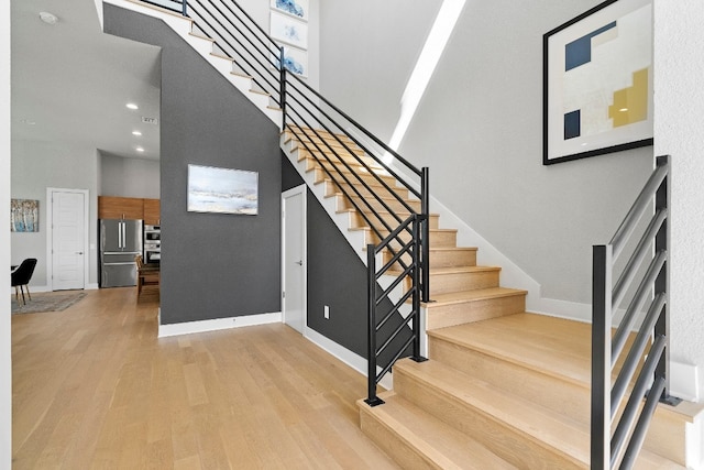 stairs with light hardwood / wood-style floors and a high ceiling