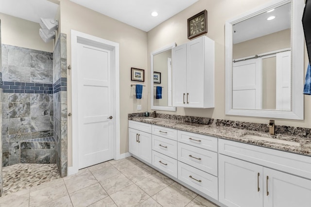 bathroom featuring tile flooring, double sink vanity, and a tile shower