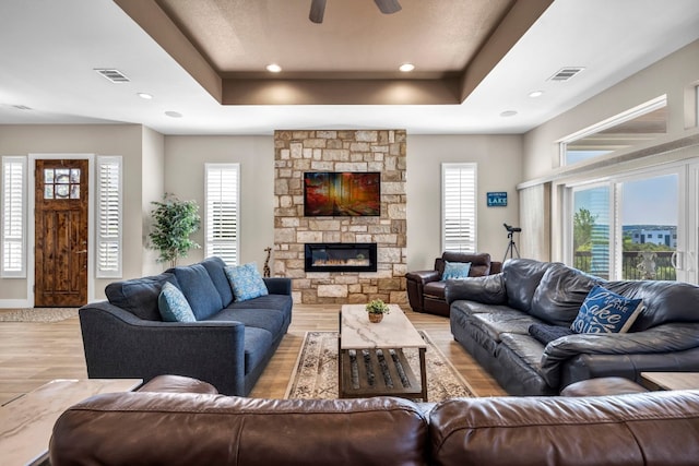 living room with a tray ceiling, plenty of natural light, and light hardwood / wood-style floors