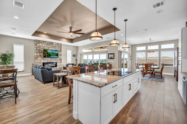 kitchen with a fireplace, a raised ceiling, decorative light fixtures, and white cabinetry