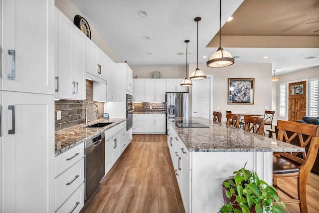 kitchen featuring a center island, dishwashing machine, light wood-type flooring, sink, and tasteful backsplash