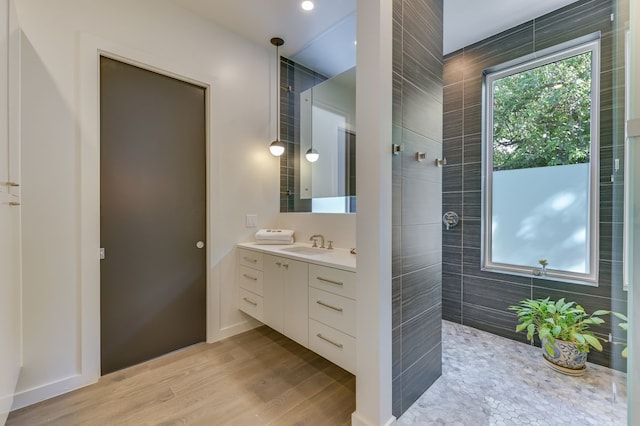 bathroom with hardwood / wood-style floors, walk in shower, and vanity