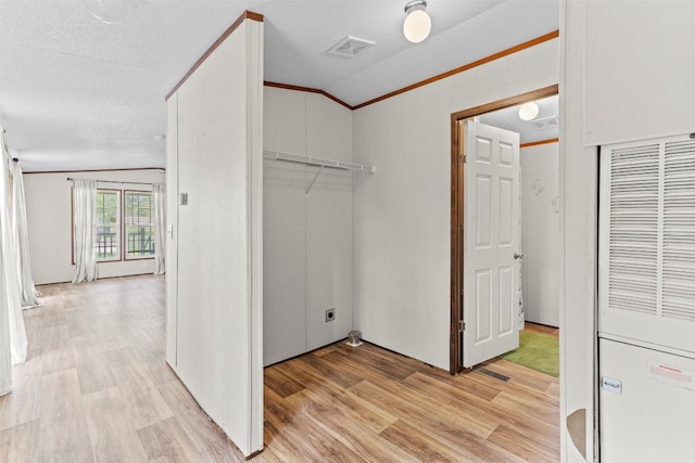 clothes washing area featuring hookup for an electric dryer, light hardwood / wood-style flooring, crown molding, and a textured ceiling