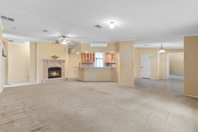 unfurnished living room featuring ceiling fan, crown molding, a fireplace, and carpet floors