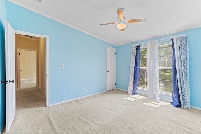 unfurnished bedroom featuring light colored carpet, ceiling fan, and ornamental molding