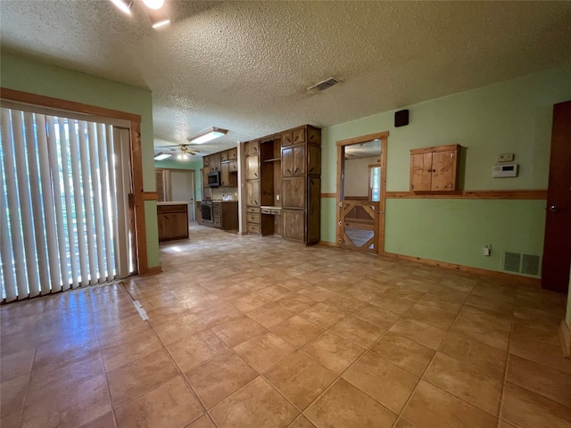 empty room with a textured ceiling, ceiling fan, and light tile floors