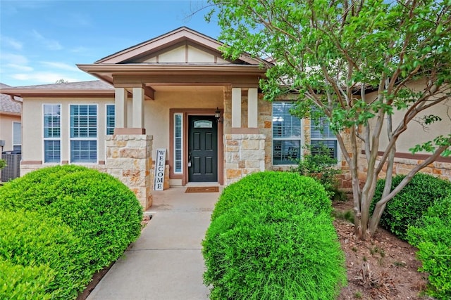 view of exterior entry featuring stone siding, central AC unit, and stucco siding