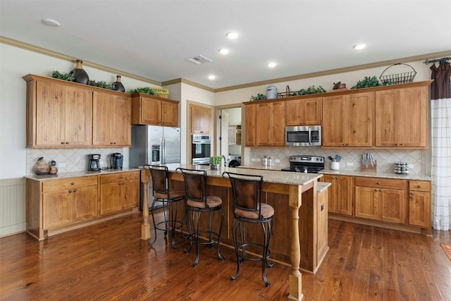 kitchen featuring appliances with stainless steel finishes, dark wood-type flooring, backsplash, and a center island with sink