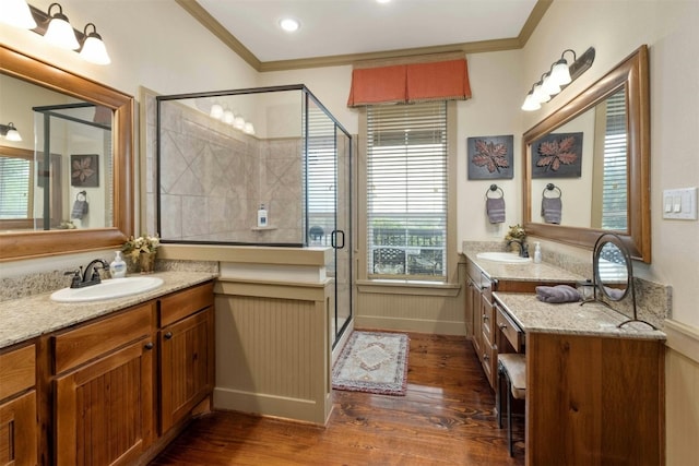 bathroom with a shower with shower door, hardwood / wood-style floors, vanity, and crown molding