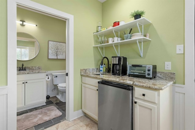 interior space with light stone countertops, light tile flooring, refrigerator, white cabinetry, and sink