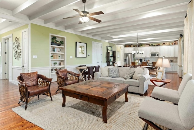 living room with built in features, beam ceiling, ceiling fan with notable chandelier, and light wood-type flooring