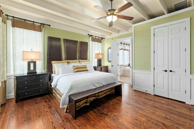 bedroom with a closet, ensuite bath, ceiling fan, dark wood-type flooring, and beamed ceiling