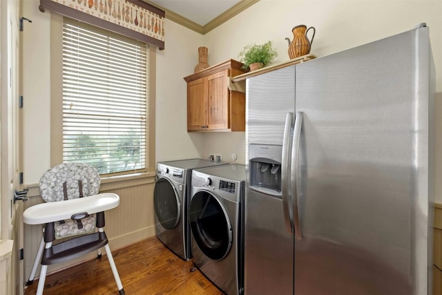 laundry room featuring hardwood / wood-style flooring, crown molding, washing machine and dryer, and cabinets