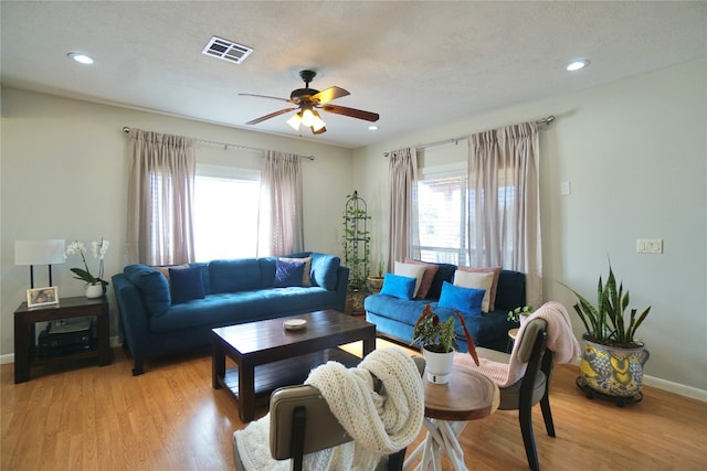 living room with a textured ceiling, light hardwood / wood-style flooring, and ceiling fan