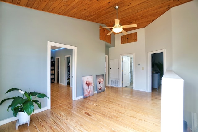 living room featuring wood ceiling, light hardwood / wood-style flooring, ceiling fan, and a towering ceiling