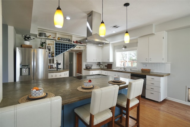 kitchen with hanging light fixtures, appliances with stainless steel finishes, island range hood, and a kitchen breakfast bar