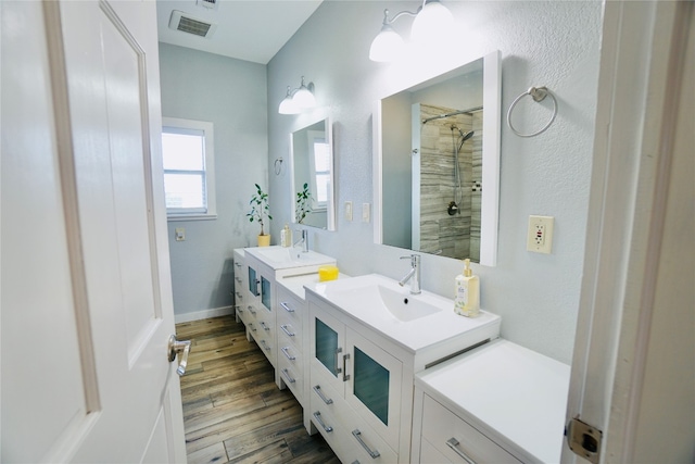 bathroom featuring vanity, hardwood / wood-style flooring, and tiled shower