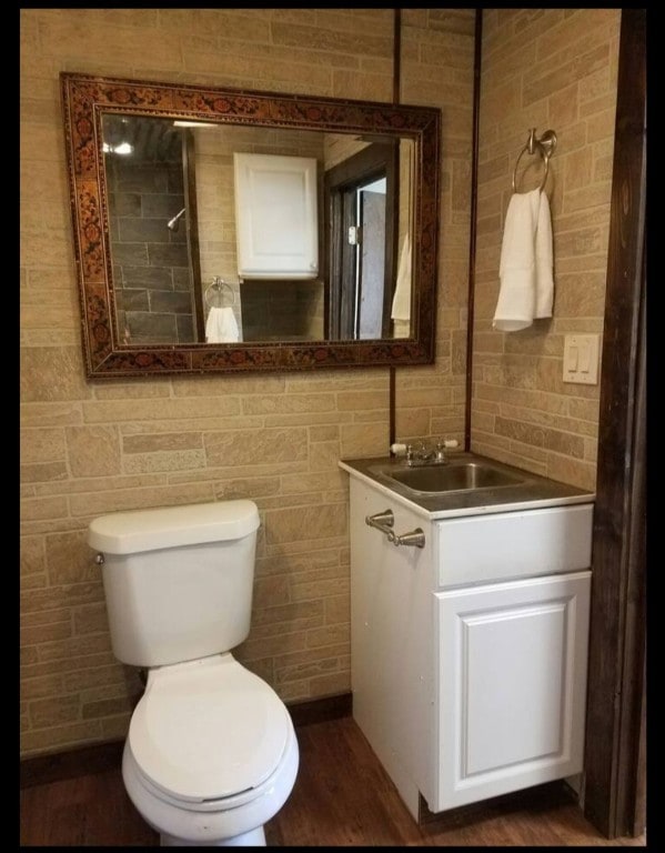 bathroom featuring hardwood / wood-style flooring, toilet, vanity, and tile walls