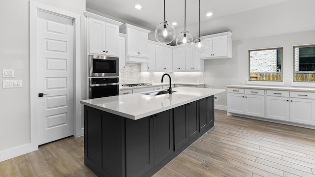 kitchen with white cabinetry, sink, an island with sink, and stainless steel appliances