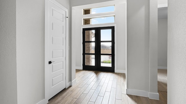 entryway with french doors, light hardwood / wood-style floors, and a healthy amount of sunlight